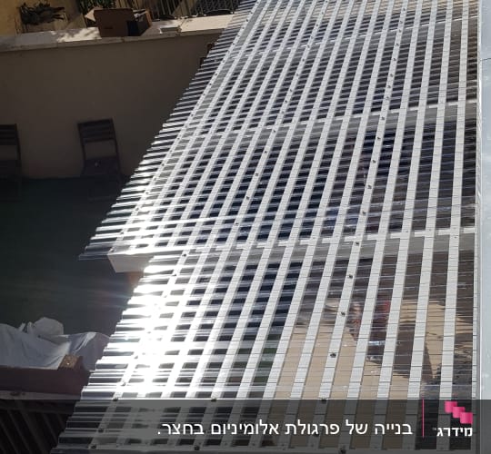 פרגולת עץ לבנה במרפסת עם קירוי סנטף שקוף ומסור עבודה
